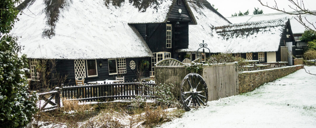 Thatch roof cottage covered in show in the winter