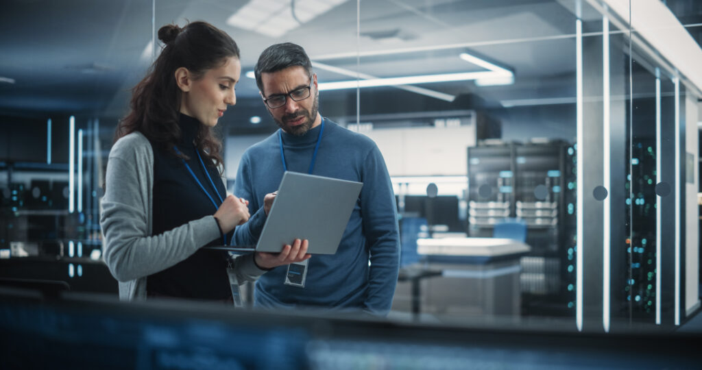 Portrait of Two Female and Male Engineers Using Laptop Computer