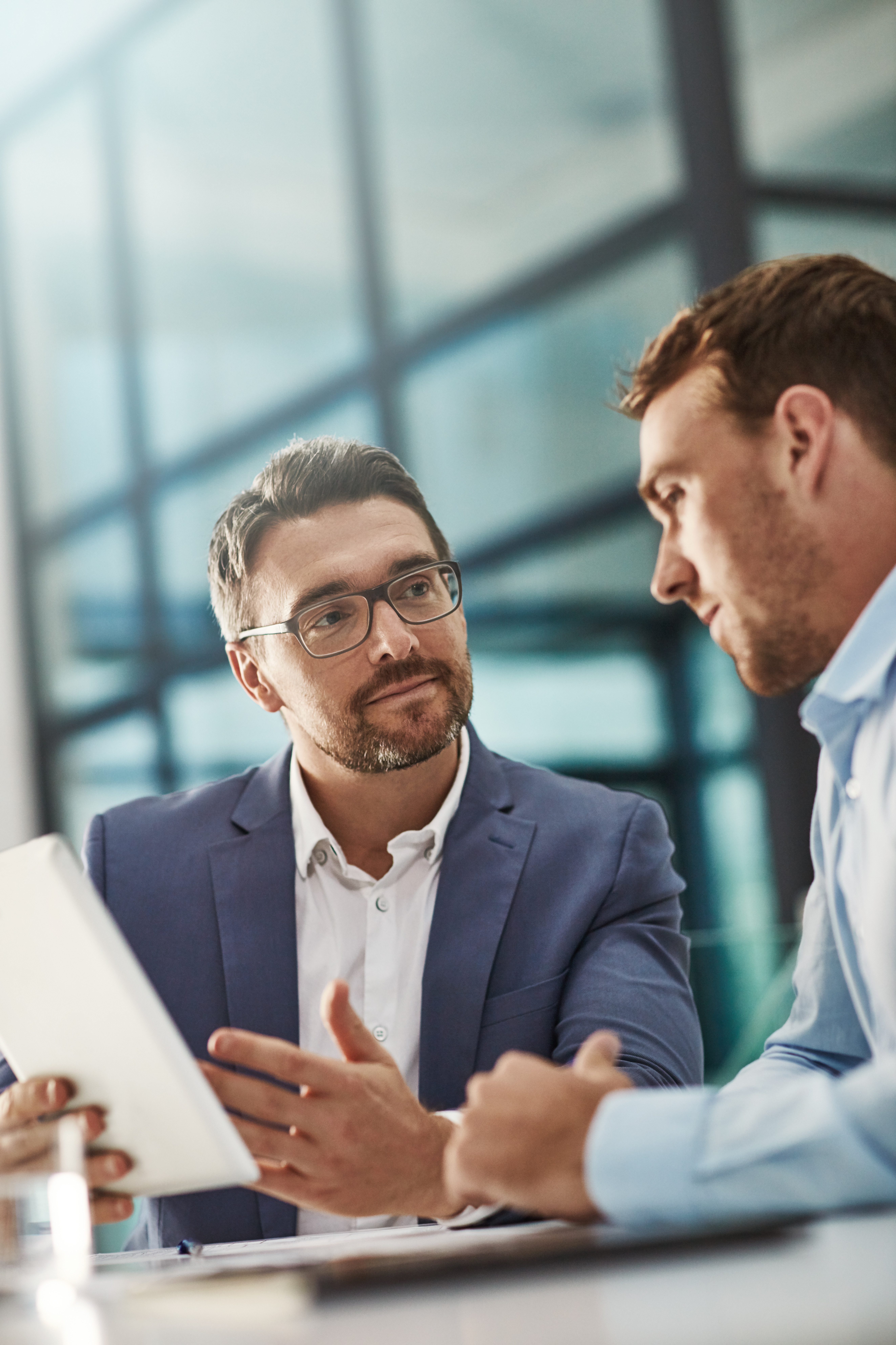 Coaching, training and business people with tablet in office workplace. Collaboration, mentor and men or employees with technology planning sales, marketing or advertising strategy in company meeting